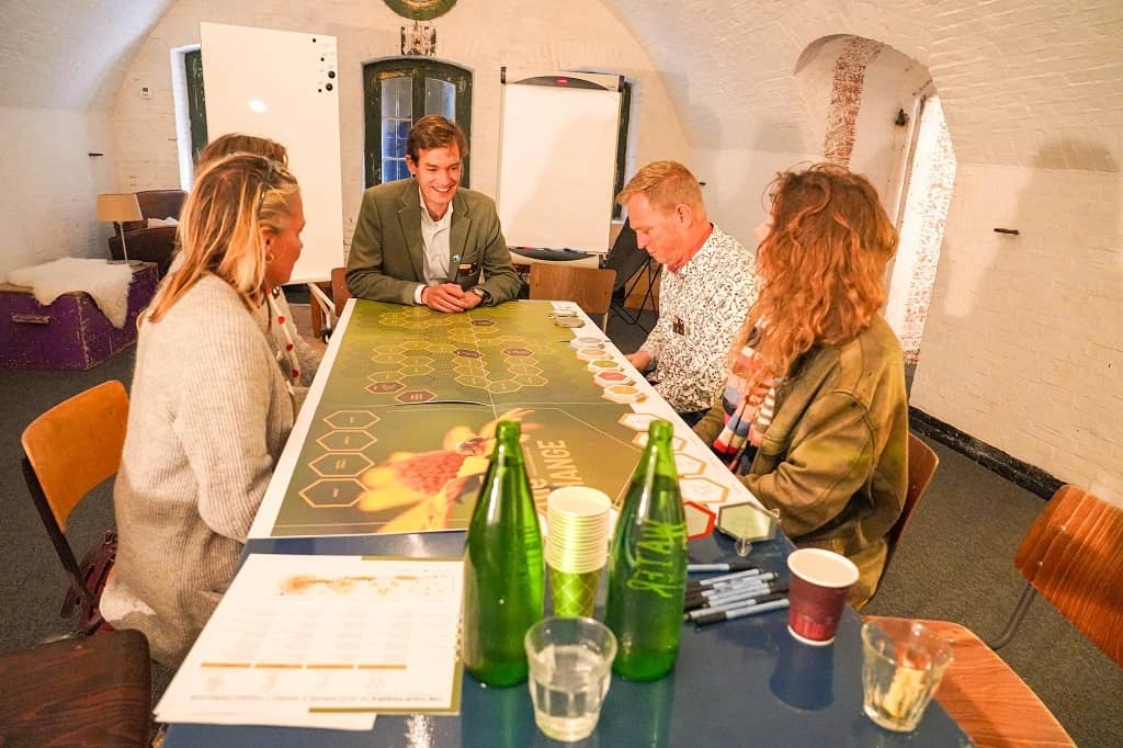 Deelnemers zitten rondom het spelbord