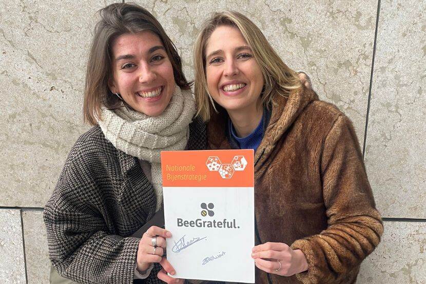 Zoe van Helvoirt en Florence van Haastrecht staan voor een muur met het ondertekeningsbordje van de Nationale Bijenstrategie