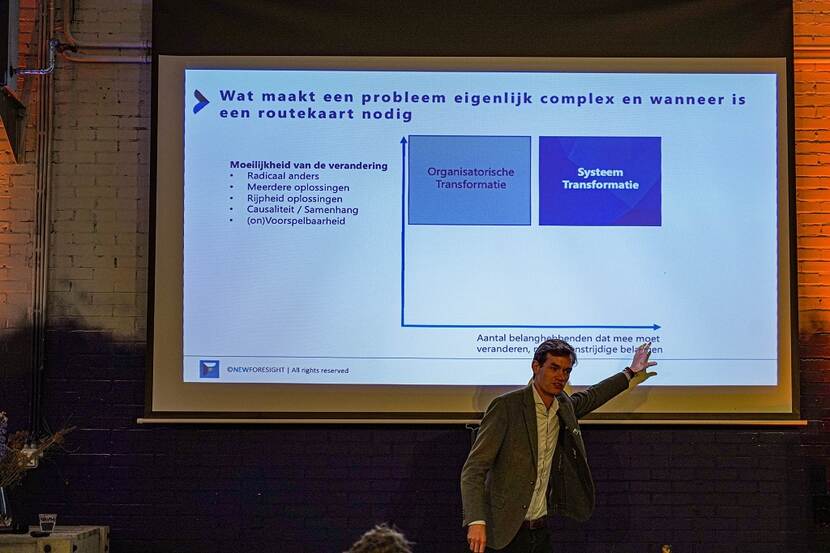 Maarten Tuinhof wijst naar een slide over Wat een probleem complex maakt. En wanneer een routekaart nodig is.