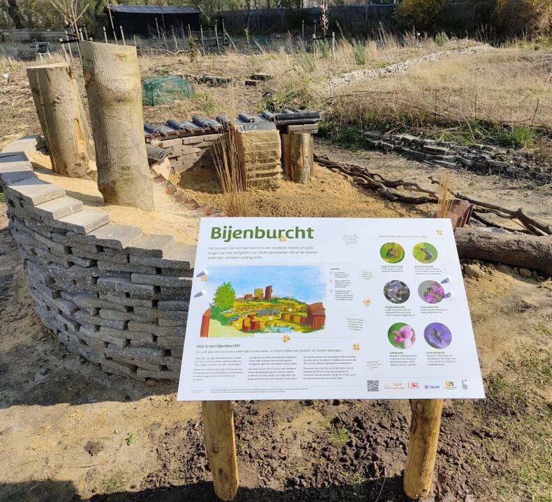 Een bijenburcht met een informatiebord met uitleg